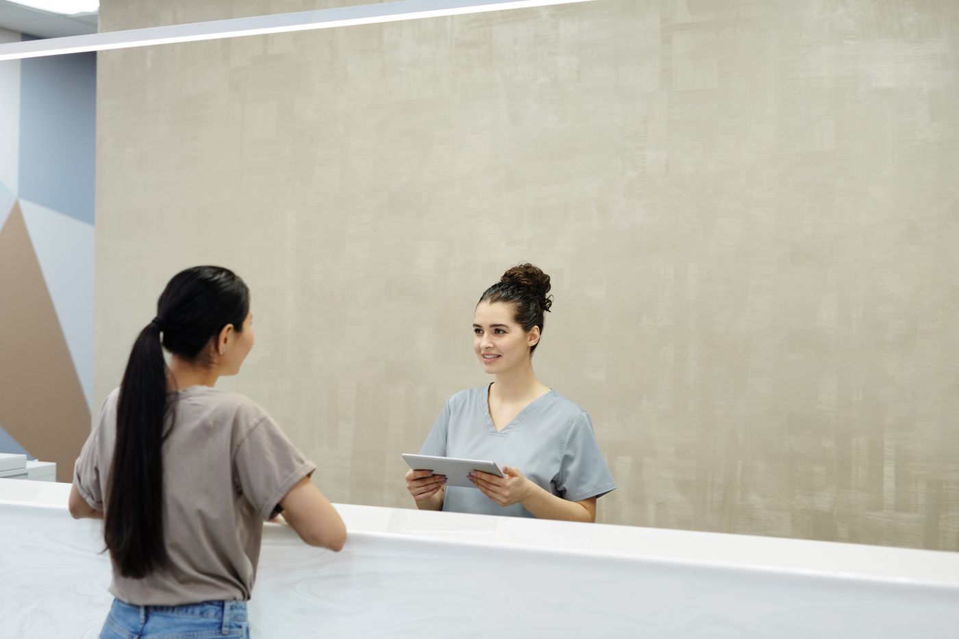 A receptionist with a tablet speaking with a patient