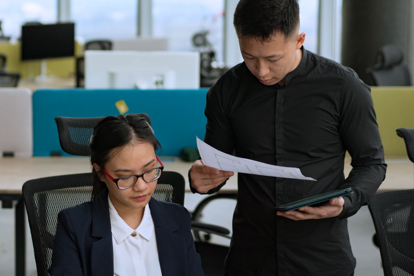 An engineer going through a document with a colleague at a desk